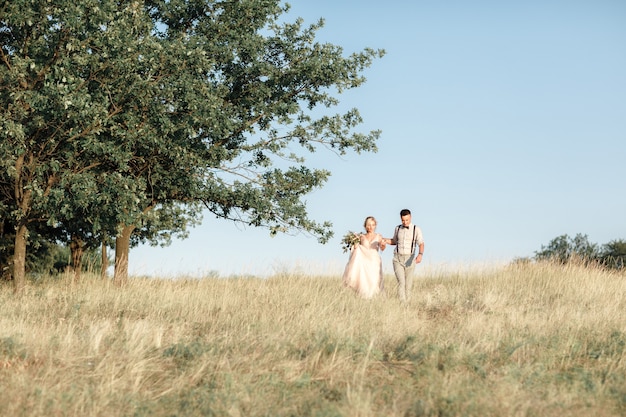 Couple de mariage sur la nature en journée d'été. la mariée et le marié étreignant au mariage.