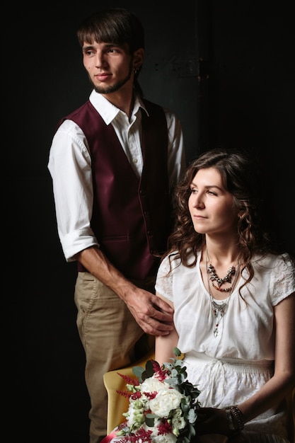 Couple de mariage posant dans l'intérieur sombre