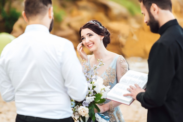 Couple de mariage près de l'océan avec un prêtre