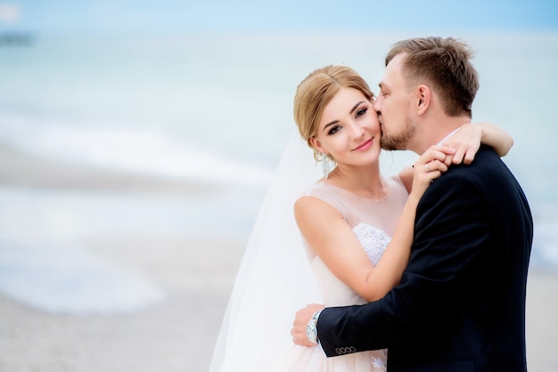 Couple de mariage rêveur câlin mutuellement debout sur la plage