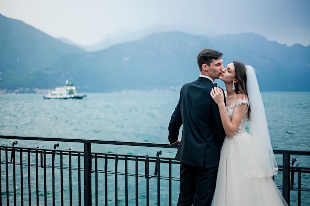 Couple de mariage s'embrassant sur le fond d'un lac et des montagnes