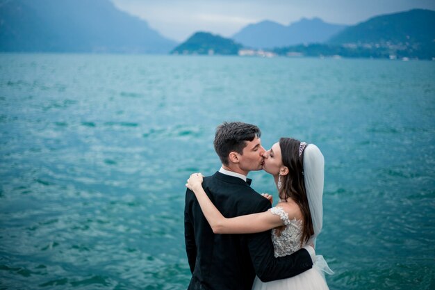 Couple de mariage s'embrassant sur le fond d'un lac et des montagnes