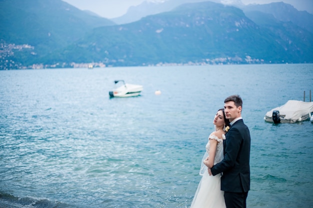 Couple de mariage s'embrassant sur le fond d'un lac et des montagnes