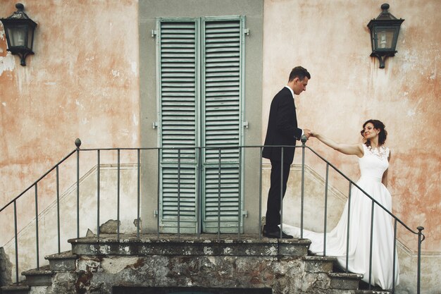 Couple de mariage se tient sur les traces devant une villa italienne orange