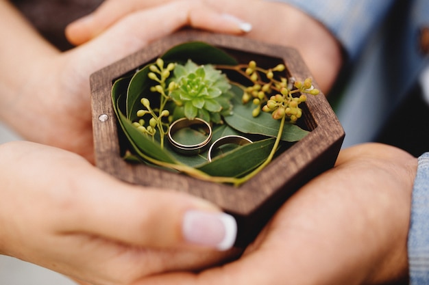 Le couple de mariage tient leurs anneaux de mariage. Photo de haute qualité