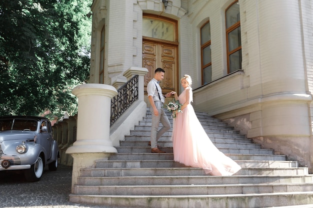 Couple de mariage en ville en journée d'été ensoleillée. la mariée et le marié se serrant dans les escaliers