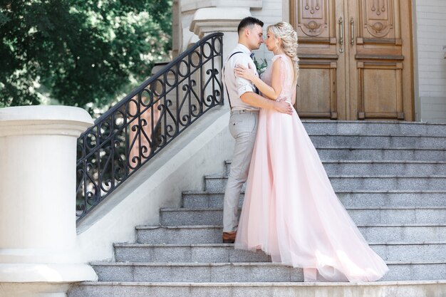 Couple de mariage en ville en journée d'été ensoleillée. la mariée et le marié se serrant dans les escaliers