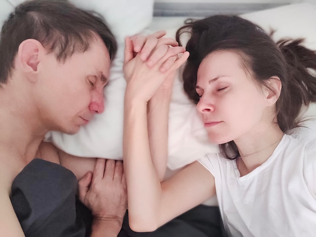 Couple marié aimant dormir et se tenir la main les yeux fermés