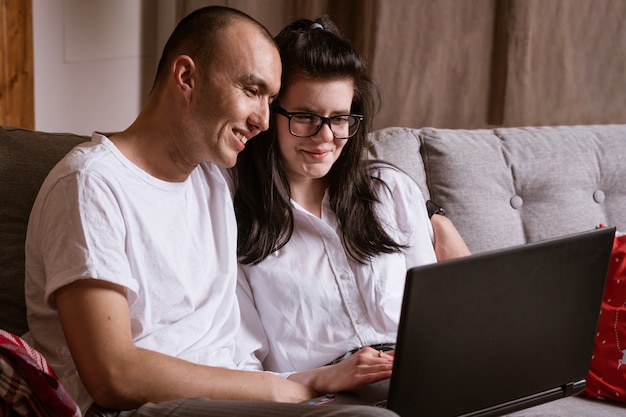 couple marié assis à la maison sur le canapé avec ordinateur portable commander des produits en ligne