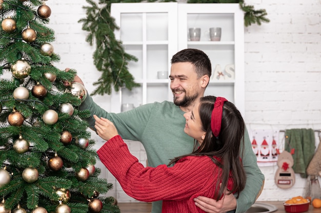 Un couple marié heureux décore un arbre de noël à la veille de noël