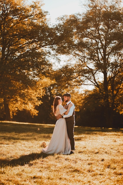 Couple marié juste marié et mariée embrassant pendant le lever du soleil dans la nature