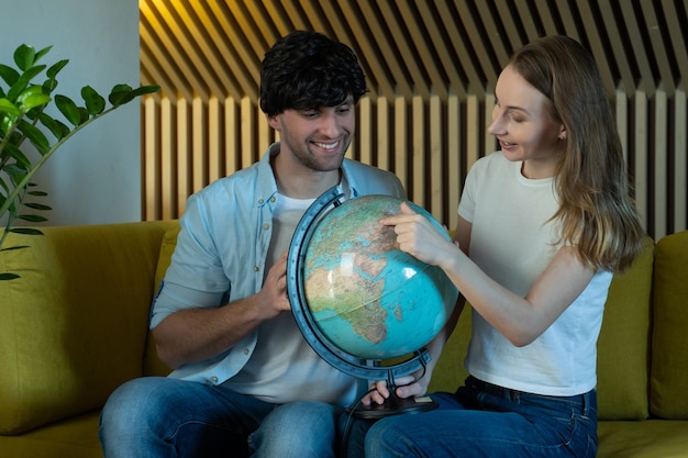 Couple Marié Regarde Le Globe Dans Le Salon Assis Sur Le Canapé Jeune Couple Choisissant Un Lieu De Voyage