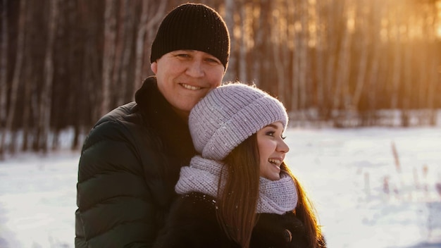 Un couple marié souriant s'embrassant en hiver près de la forêt