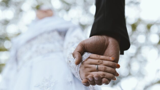 Photo couple marié tenant la main lors d'un mariage de cérémonie