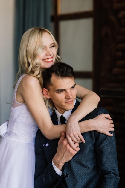 Photo un couple de mariés mignons à l'intérieur d'un studio classique décoré ils s'embrassent et s'étreignent