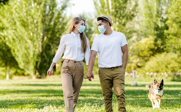 Couple avec masque de protection marchant dans le parc