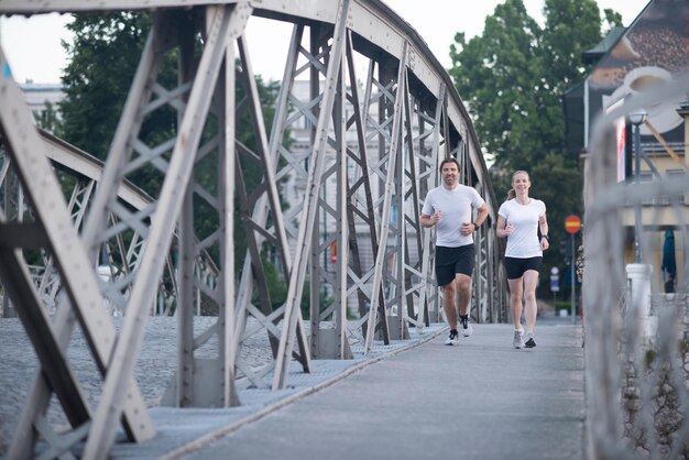 couple mature en bonne santé faisant du jogging dans la ville tôt le matin avec le lever du soleil en arrière-plan