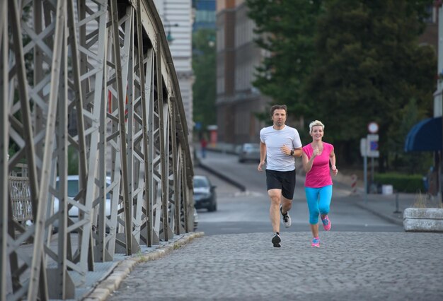 couple mature en bonne santé faisant du jogging dans la ville tôt le matin avec le lever du soleil en arrière-plan