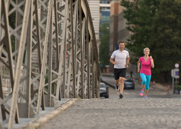 couple mature en bonne santé faisant du jogging dans la ville tôt le matin avec le lever du soleil en arrière-plan