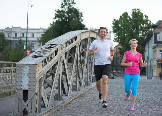 couple mature en bonne santé faisant du jogging dans la ville tôt le matin avec le lever du soleil en arrière-plan