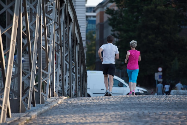 couple mature en bonne santé faisant du jogging dans la ville tôt le matin avec le lever du soleil en arrière-plan