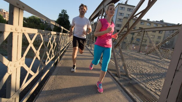 couple mature en bonne santé faisant du jogging dans la ville tôt le matin avec le lever du soleil en arrière-plan