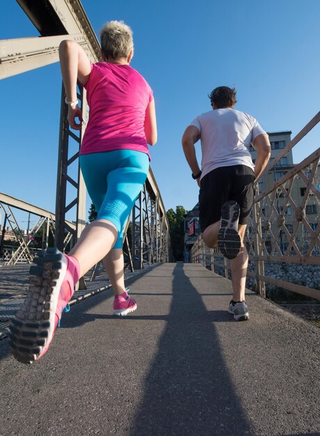 couple mature en bonne santé faisant du jogging dans la ville tôt le matin avec le lever du soleil en arrière-plan