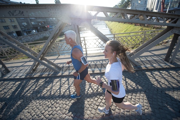 couple mature en bonne santé faisant du jogging dans la ville tôt le matin avec le lever du soleil en arrière-plan