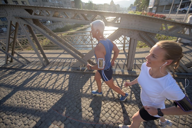 couple mature en bonne santé faisant du jogging dans la ville tôt le matin avec le lever du soleil en arrière-plan