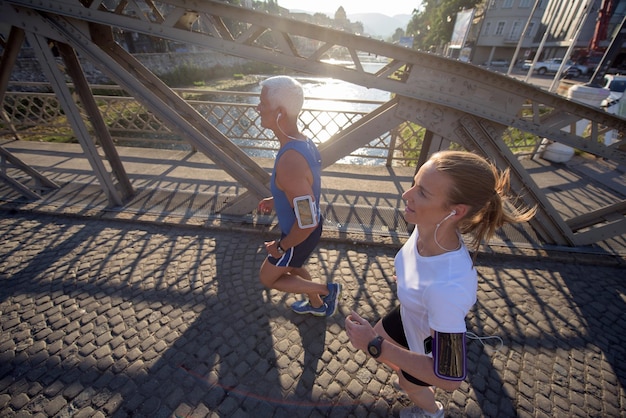 couple mature en bonne santé faisant du jogging dans la ville tôt le matin avec le lever du soleil en arrière-plan