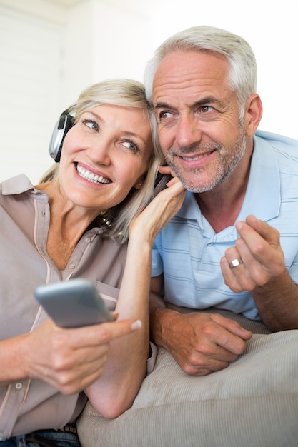 Couple mature gai avec un casque et un téléphone portable