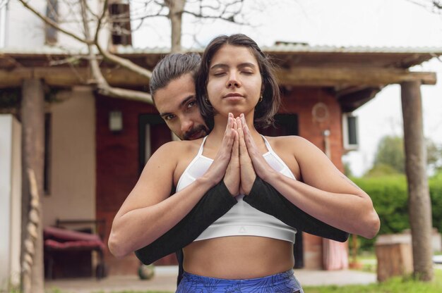 Un couple en méditation tenant leurs paumes ensemble à l'extérieur