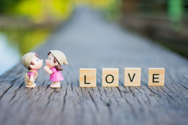 Couple miniature love kiss sur la table en bois et le texte en bois LOVE.