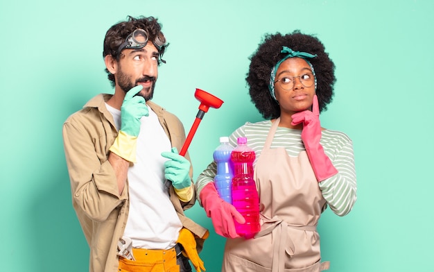 Photo couple mixte souriant joyeusement et doutant à la recherche sur le côté concept d'entretien ménager concept de réparations à domicile