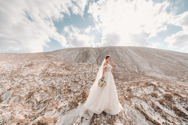 Couple à la mode et beau, fille modèle blonde heureuse avec une coiffure élégante, dans une robe en dentelle blanche et bel homme élégant dans le costume à la mode sur la montagne de sel.