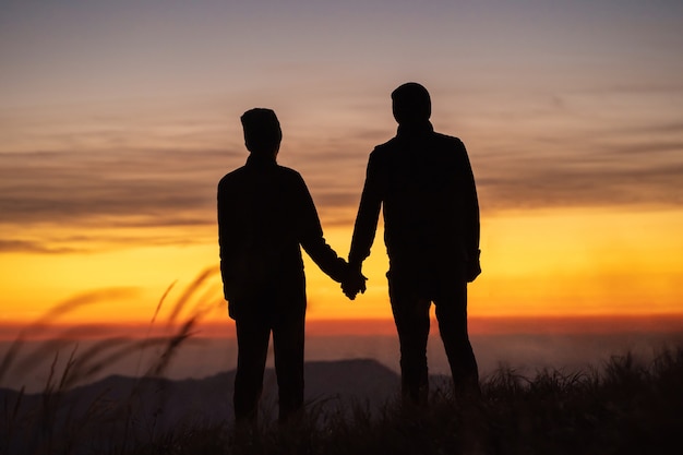 Le couple sur la montagne profitant d'un fond pittoresque de coucher de soleil