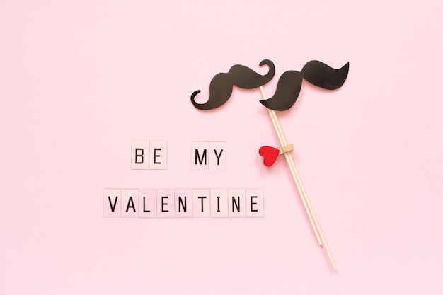 Couple de moustaches en papier sur le stick et le texte Be my Valentine on pink