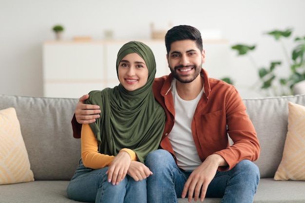 Couple moyen-oriental avec femme portant le hijab embrassant à la maison