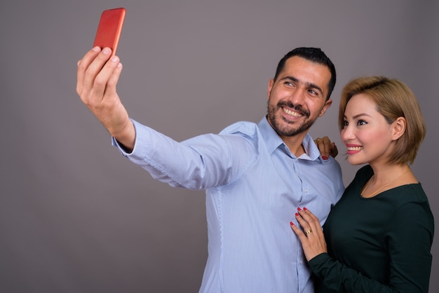 Couple multiethnique amoureux contre mur gris