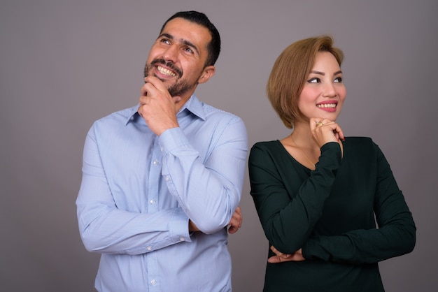 Couple multiethnique amoureux contre mur gris