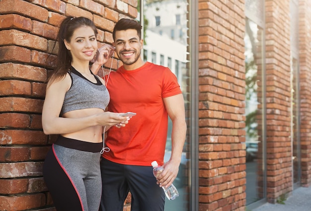 Un couple multiethnique se détend de l'exercice en écoutant de la musique sur un smartphone, copiez l'espace