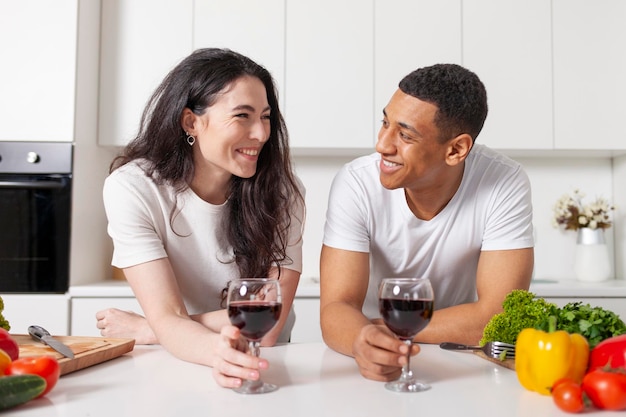 Couple multiracial buvant du vin dans la cuisine et parlant américain et fille européenne