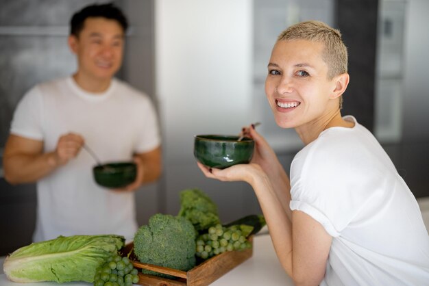 Couple multiracial mangeant de la salade dans la cuisine à la maison