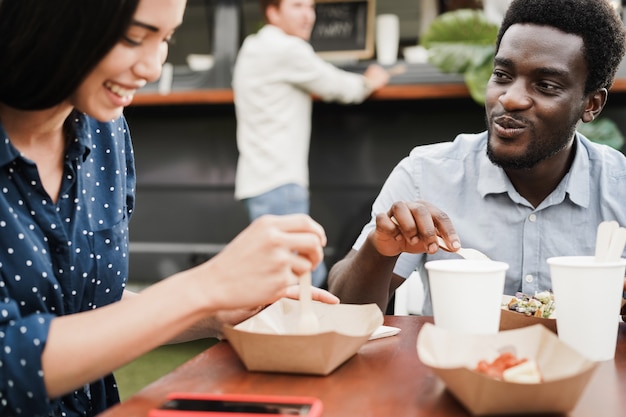 Couple multiracial s'amusant à manger au restaurant de camion de nourriture en plein air - Focus sur le visage de l'homme afro-américain