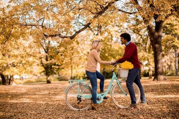 Couple multiracial avec vélo dans le parc en automne