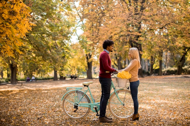 Couple multiracial avec vélo dans le parc en automne