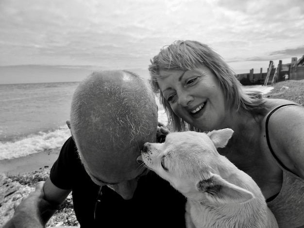 Photo un couple mûr avec un chien au bord de la plage