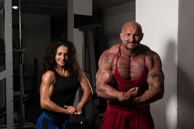 Couple de musculation impressionnant montrant leurs muscles et posant dans une salle de sport