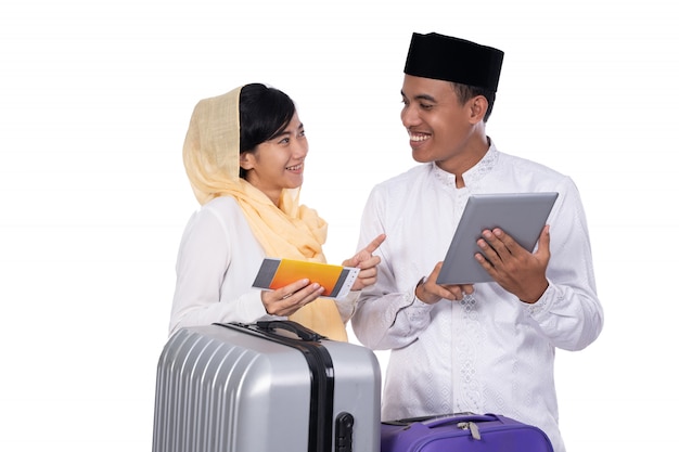 Couple musulman avec valise à l'aide de tablette ensemble