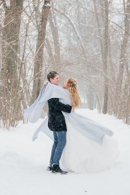 Couple sur la nature en hiver lors d'une chute de neige